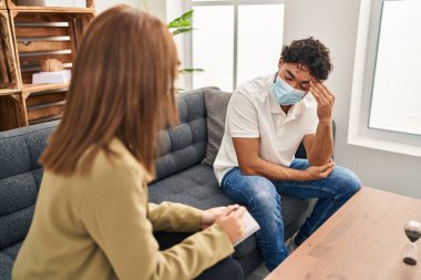 Man and woman wearing medical mask having psychology session at psychology center