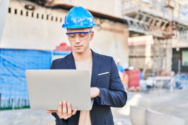 Young hispanic man architect using laptop at street