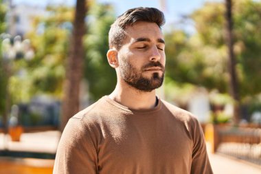 Genç İspanyol adam gülümsüyor. Parkta nefes alıyor.