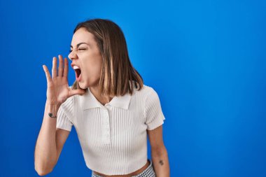 Mavi arka planda dikilen İspanyol kadın avazı çıktığı kadar bağırıyor ve bağırıyordu. iletişim konsepti. 