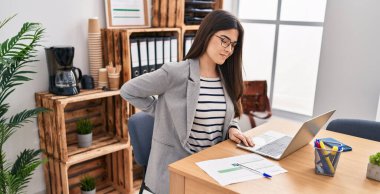 Genç ve güzel İspanyol iş kadını ofiste sırt ağrısı çekiyor.