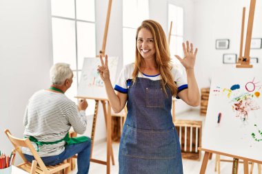 Resim stüdyosunda önlük giyen İspanyol kadın yedi numarayı gösterip işaret ederken kendine güvenen ve mutlu bir şekilde gülümsüyor.. 