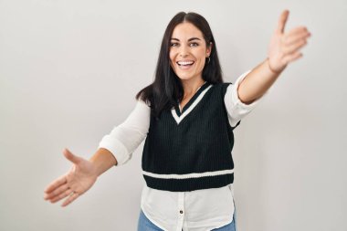 Soyutlanmış arka planda duran genç İspanyol kadın kameraya sarılmak için kollarını açıp gülümseyerek bakıyor. Mutluluğu kucaklayan neşeli bir ifade.. 