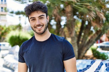 Genç İspanyol adam gülümseyerek şehirde mutlu mesut dikiliyor..