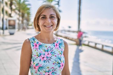 Orta yaşlı, güzel bir kadın. Deniz kenarında kendine güvenen.