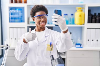 Afrika kökenli Amerikalı bir kadın bilim adamının laboratuarında çalışıyor. Akıllı telefonuyla video görüşmesi yapıyor. Mutlu ve olumlu gülümsüyor. 
