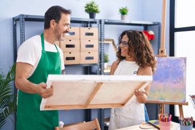 Man and woman artists smiling confident looking draw at art studio