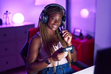 Oyun odasında joystick kullanarak video oyunu oynayan Afro-Amerikan kadın flaması.