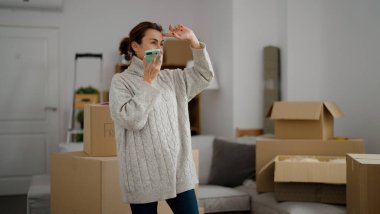 Orta yaşlı İspanyol kadın gülümsüyor. Yeni evindeki akıllı telefondan konuşuyor.