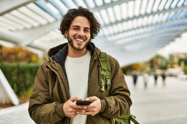 Şehirde akıllı telefon kullanan yakışıklı bir İspanyol.