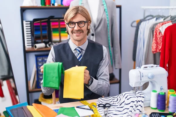 Jonge Blonde Man Kleermaker Glimlachen Zelfverzekerde Holding Doeken Kleding Fabriek — Stockfoto