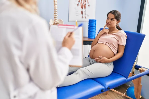 Mujer Embarazada Joven Fisioterapeuta Clínica Escéptica Nerviosa Frunciendo Ceño Molesto — Foto de Stock