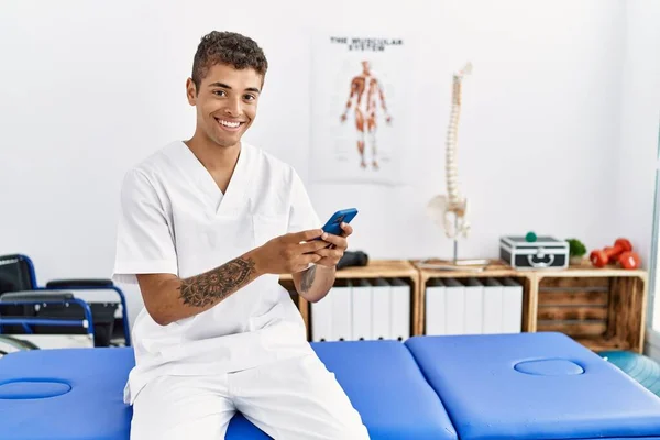 Joven Hombre Hispano Trabajando Como Fisioterapeuta Usando Smartphone Sala Fisioterapia — Foto de Stock