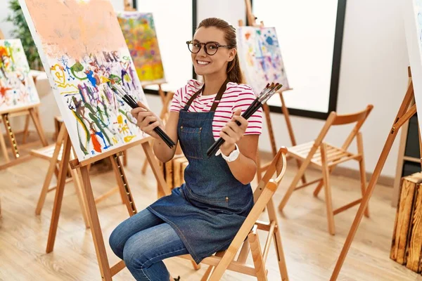 Mujer Joven Sonriendo Confiada Sosteniendo Pinceles Estudio Arte —  Fotos de Stock