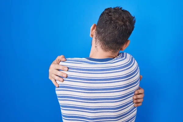 Νεαρός Ισπανός Που Στέκεται Πάνω Από Μπλε Φόντο Αγκαλιάζοντας Τον — Φωτογραφία Αρχείου
