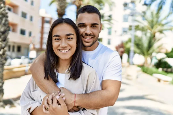 年轻的拉丁夫妇在城市里欢快地微笑着 拥抱着 — 图库照片