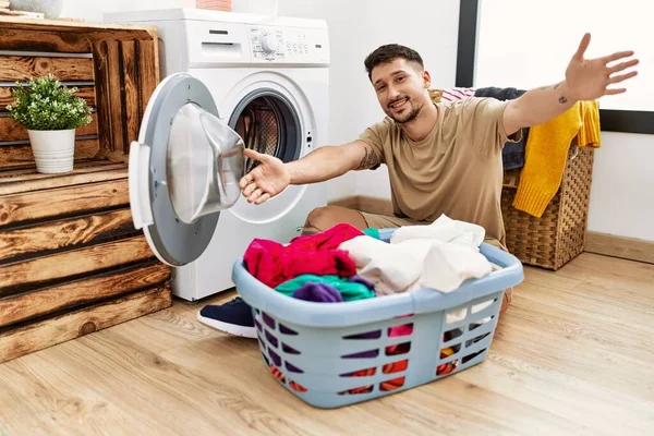 Çamaşır Makinesine Kirli Çamaşırlarını Koyan Yakışıklı Genç Bir Adam Kameraya — Stok fotoğraf