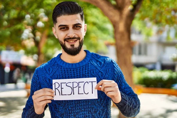 Young arab man smiling confident holding respect banner at park