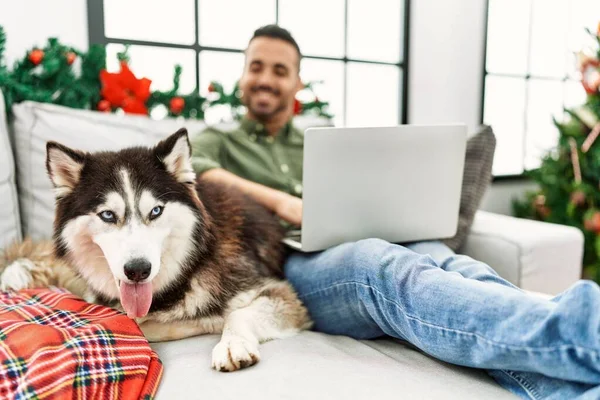 Jovem Hispânico Usando Laptop Sentado Sofá Com Cão Pela Árvore — Fotografia de Stock