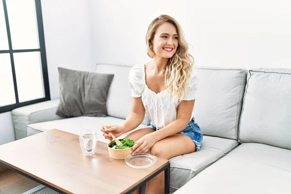 Young Woman Eating Salad Sitting Sofa Home —  Fotos de Stock