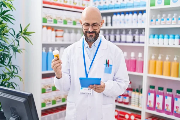 Giovane Farmacista Uomo Calvo Utilizzando Touchpad Possesso Pillole Bottiglia Farmacia — Foto Stock