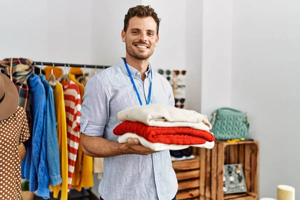 Jovem Lojista Hispânico Homem Sorrindo Feliz Segurando Pilha Suéter Loja — Fotografia de Stock