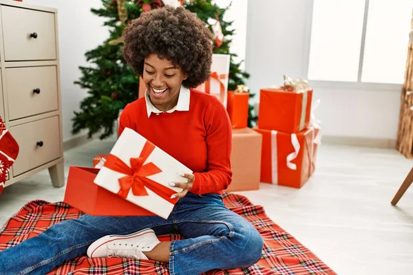 Young African American Woman Unboxing Gift Sitting Christmas Tree Home — ストック写真