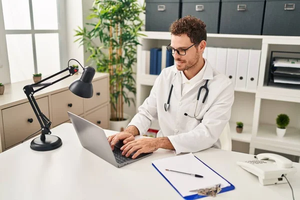 Young Hispanic Man Wearing Doctor Uniform Using Laptop Clinic — Stok fotoğraf