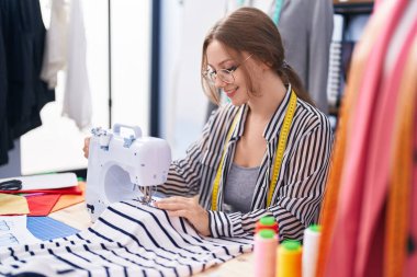 Terzide dikiş makinesi kullanan kendine güvenen genç sarışın kadın terzi.