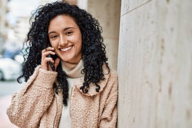 Genç İspanyol kadın gülümsüyor. Kendine güveniyor. Akıllı telefondan konuşuyor.