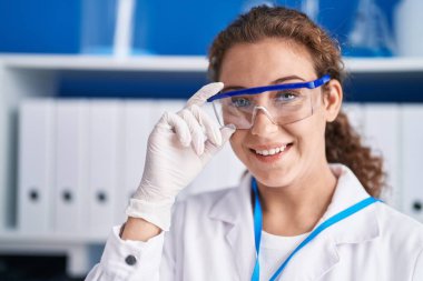 Young beautiful hispanic woman scientist smiling confident standing at laboratory