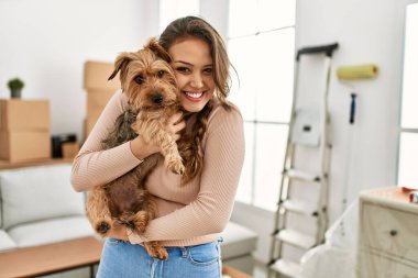 Genç, güzel, İspanyol bir kadın gülümsüyor. Yeni evinde kendine güvenen bir köpek.