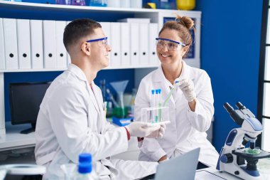 Man and woman scientists holding test tubes at laboratory