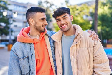 İki erkek parkta birbirlerine sarılıyorlar.