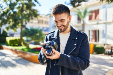 Parktaki profesyonel kamerayla gülümseyen İspanyol genç adam.