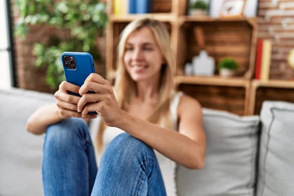 Jovem Loira Usando Smartphone Sentado Sofá Casa — Fotografia de Stock