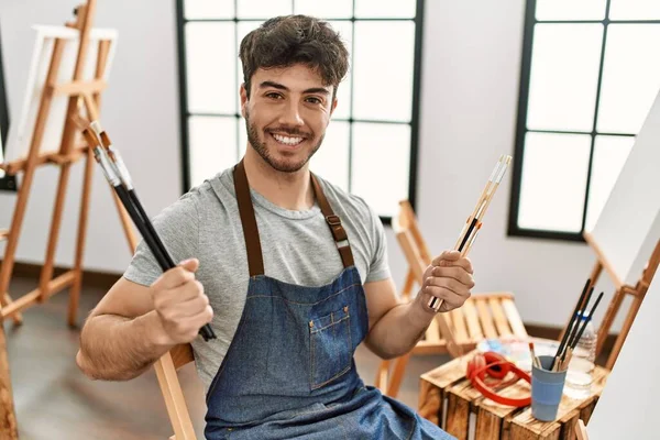 Joven Artista Hispano Sonriendo Feliz Sosteniendo Pinceles Estudio Arte — Foto de Stock