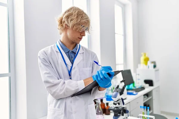 Joven Hombre Rubio Científico Escribiendo Informe Trabajo Laboratorio —  Fotos de Stock