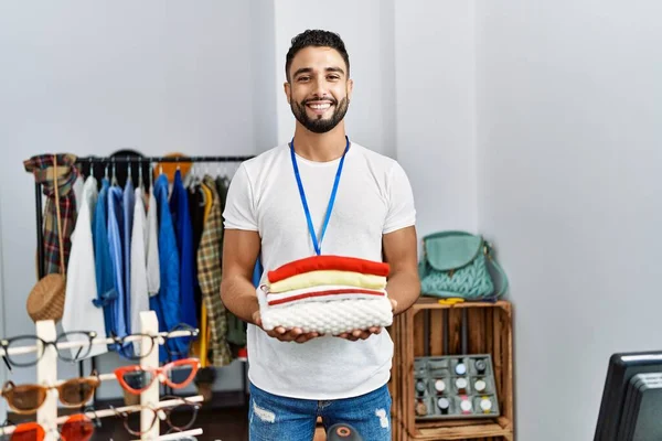Jovem Árabe Homem Lojista Segurando Roupas Dobradas Trabalhando Loja Roupas — Fotografia de Stock