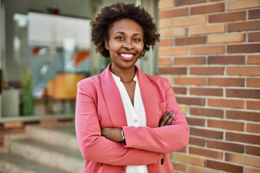 Güzel bir iş adamı Afro saçlı Amerikalı kadın şehirde mutlu ve kendinden emin bir şekilde gülümsüyor.