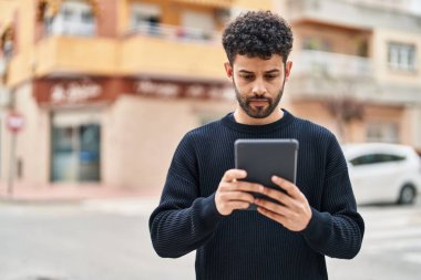 Sokakta dokunmatik ped kullanan rahat yüzlü genç bir Arap.