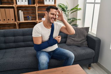 Kol askısında sakallı, genç İspanyol bir adam terapide danışmanlık yaparken mutlu mesut gülümsüyor. 