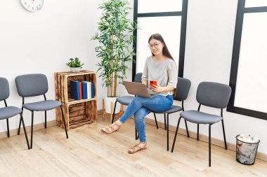 Bekleme odasında dizüstü bilgisayar kullanan Asyalı genç bir kadın.