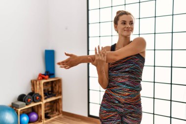 Genç bir kadın spor merkezinde kendine güvenerek gülümsüyor.