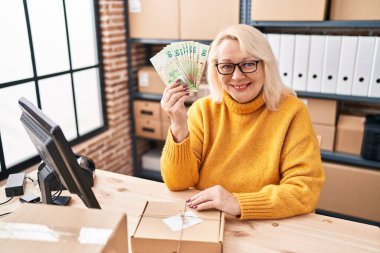 Orta yaşlı, beyaz bir kadın elinde Hong Kong dolarlarıyla küçük bir şirkette çalışıyor. Pozitif ve mutlu görünüyor. Kendine güvenen bir gülümsemeyle dişlerini gösteriyor. 
