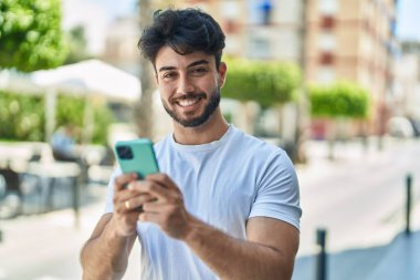 Sokakta akıllı telefon kullanan, kendine güvenen genç bir İspanyol.