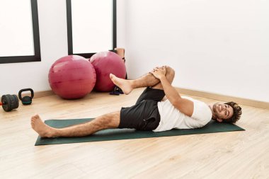 Genç İspanyol adam gülümsüyor spor merkezinde esniyor.