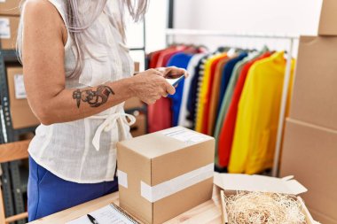 Orta yaşlı, kır saçlı, iş kadını. Ofiste fotoğraftan pakete.