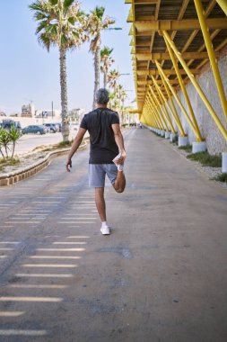 Orta yaşlı İspanyol adam spor giyer, sokakta esniyor.