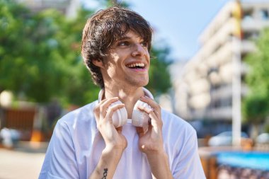 Parkta kendinden emin gülümseyen genç sarışın adam.